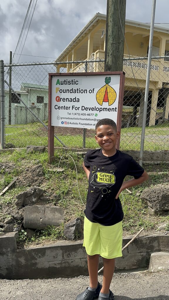 Grenada with an autistic child: my son at an autism foundation sign